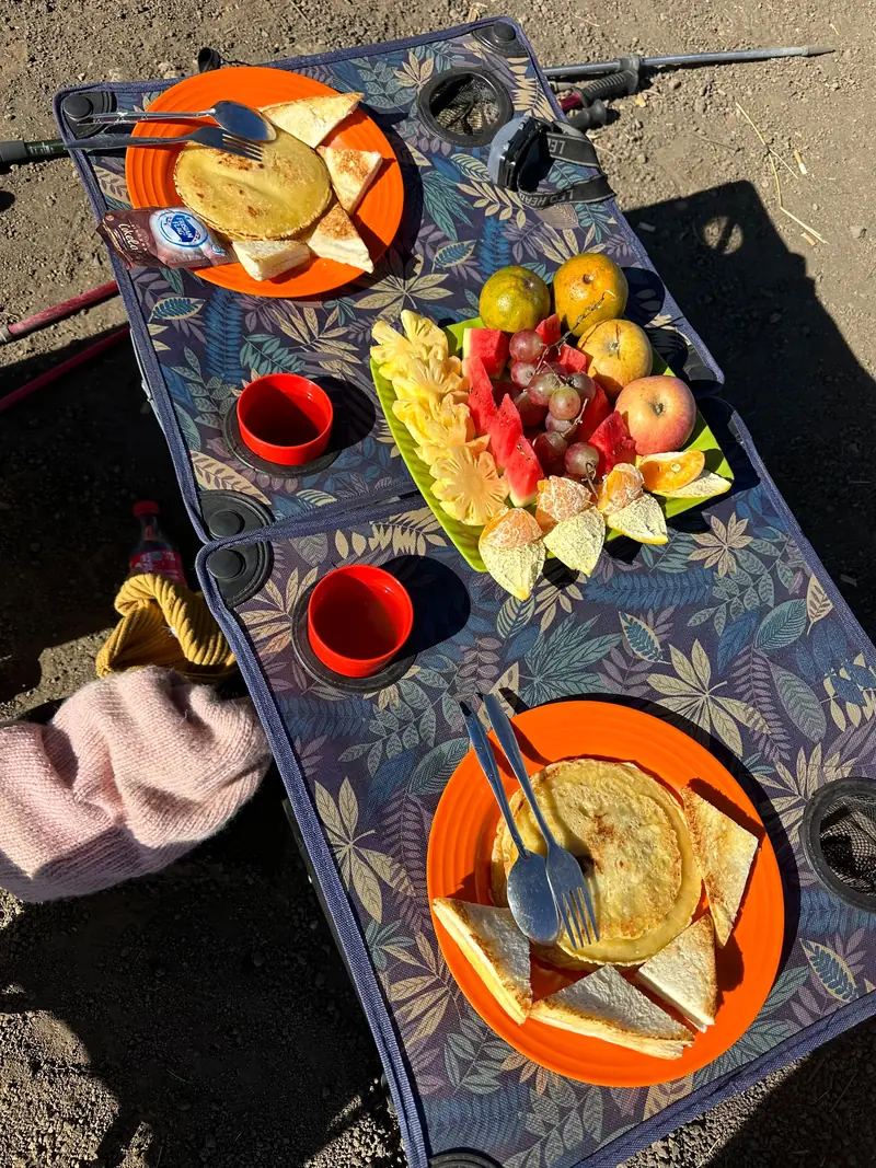 Breakfast spread laid out on the camp table: pancakes, toast and fresh fruit