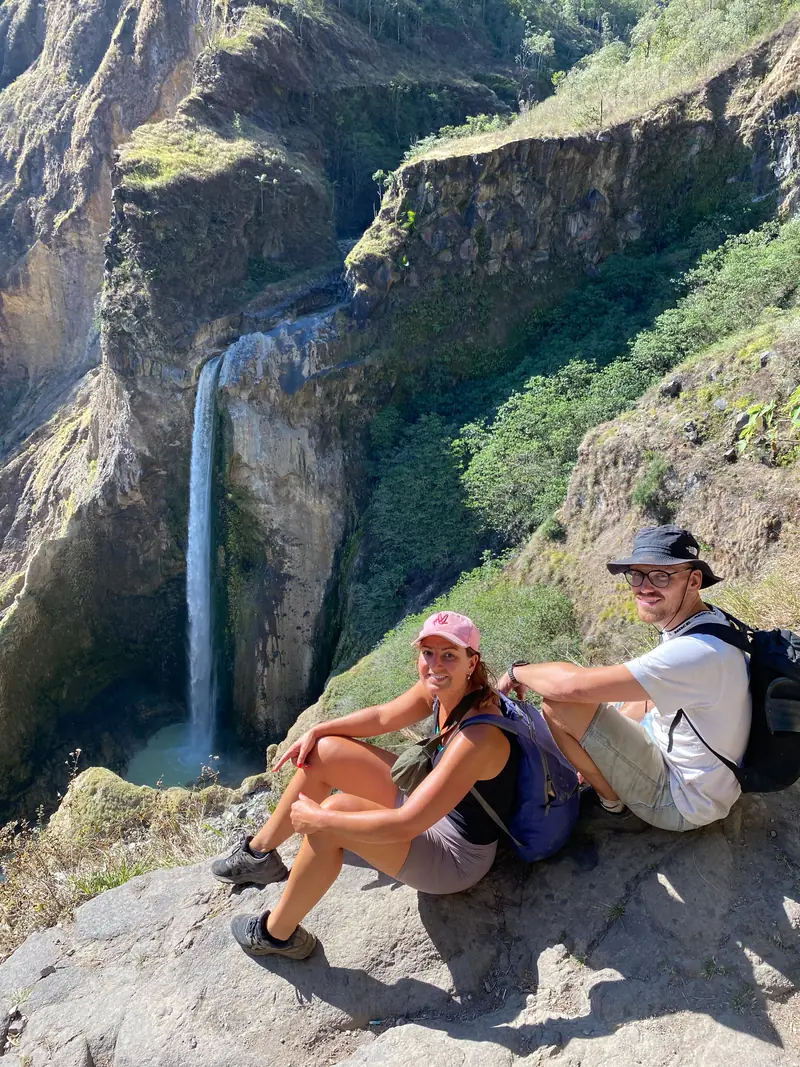 Two trekkers resting above a waterfall on the Torean descent